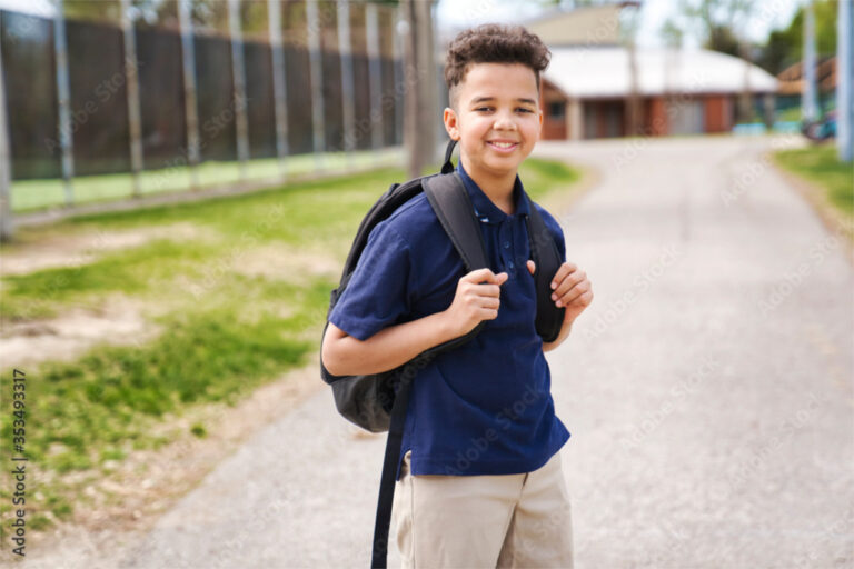 School age boy in uniform wearing a backpack